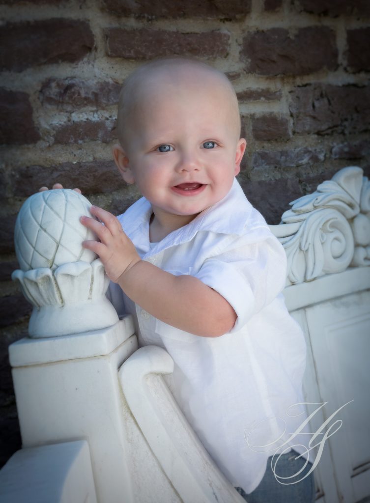 A baby in white shirt sitting on top of a chair.