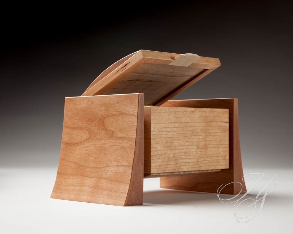 A wooden box with a lid open on top of it.