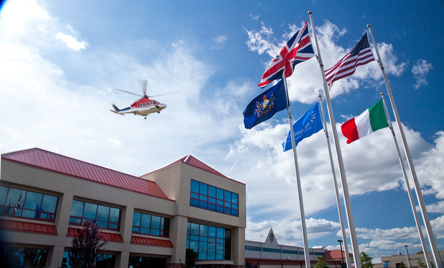 A helicopter flying over some flags in the sky.