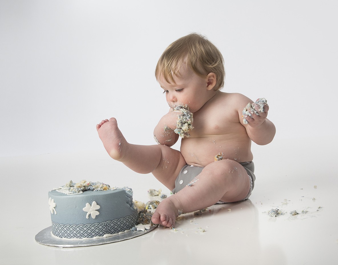 A baby sitting in front of a cake with flowers on it.