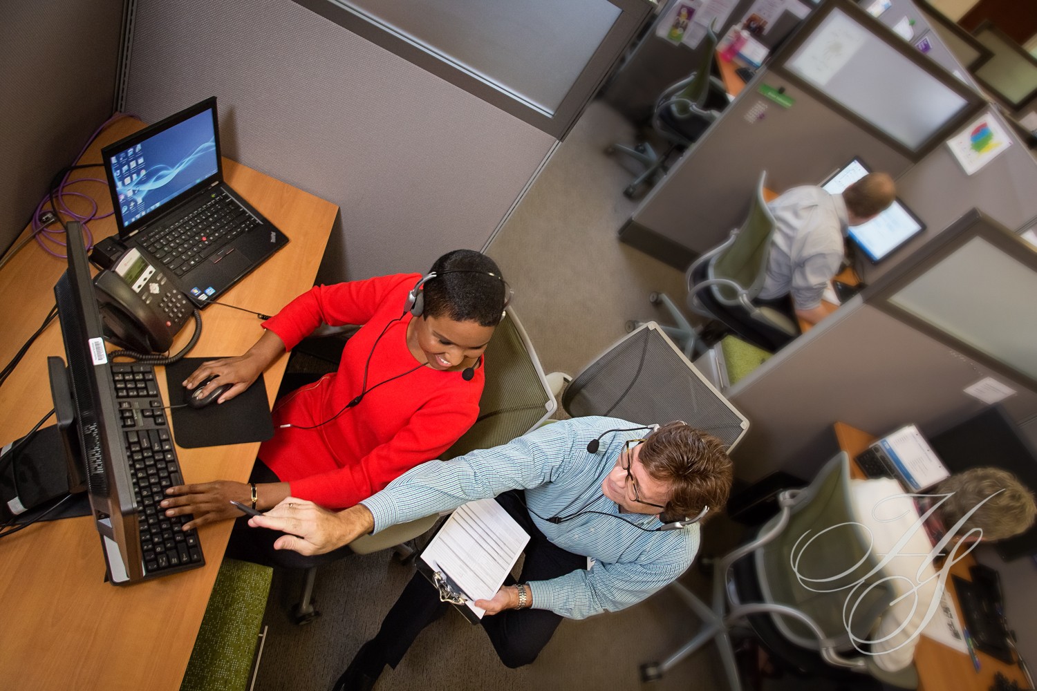 Two people sitting at a desk with laptops