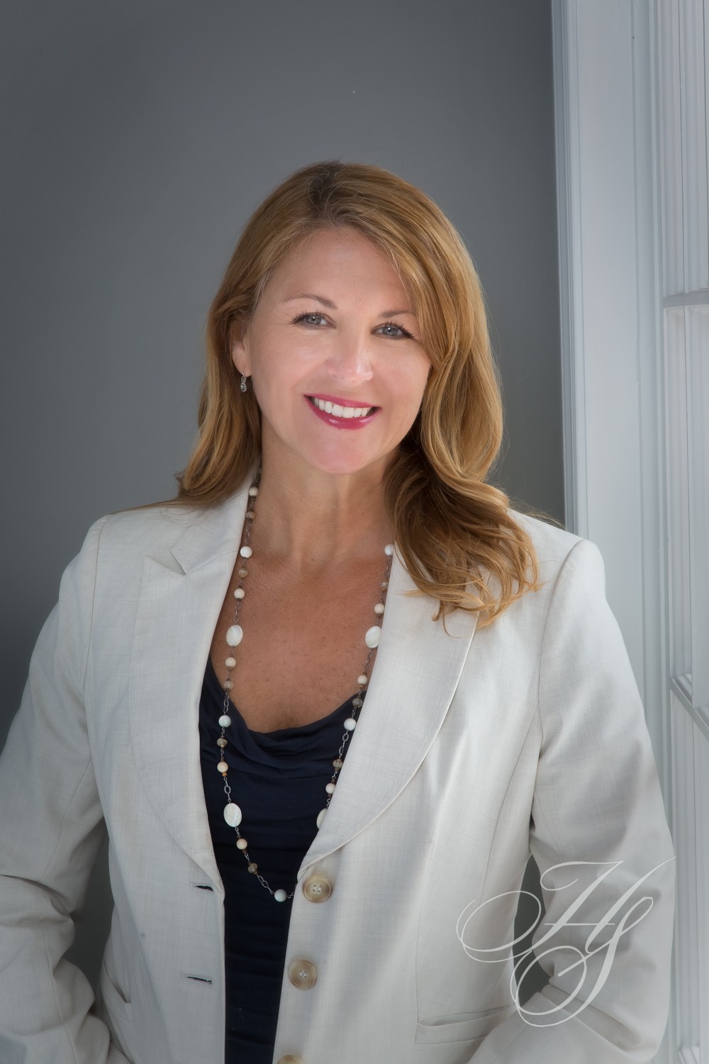 A woman in white jacket and black shirt smiling.