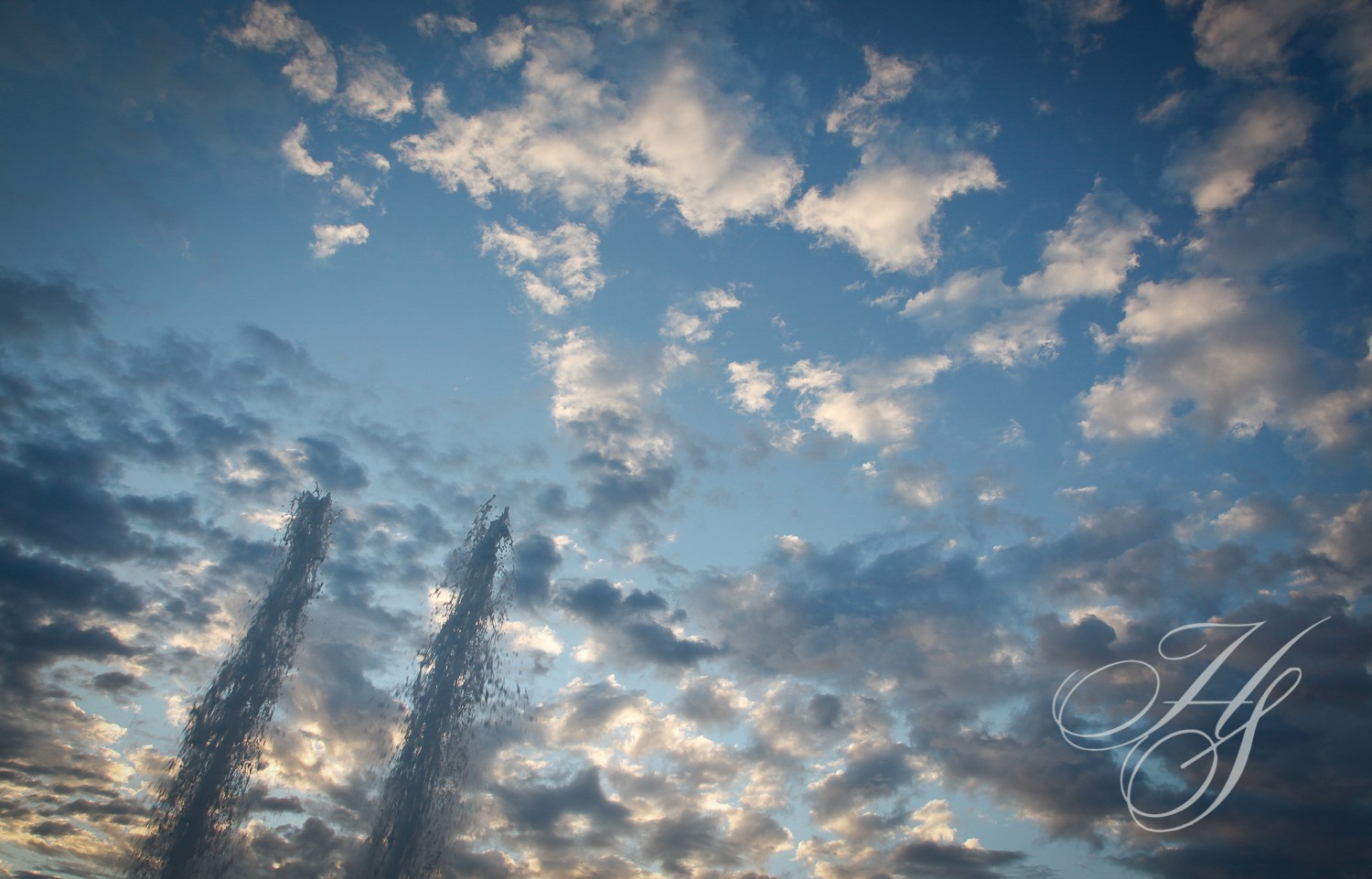 A sky filled with lots of clouds and some tall towers.