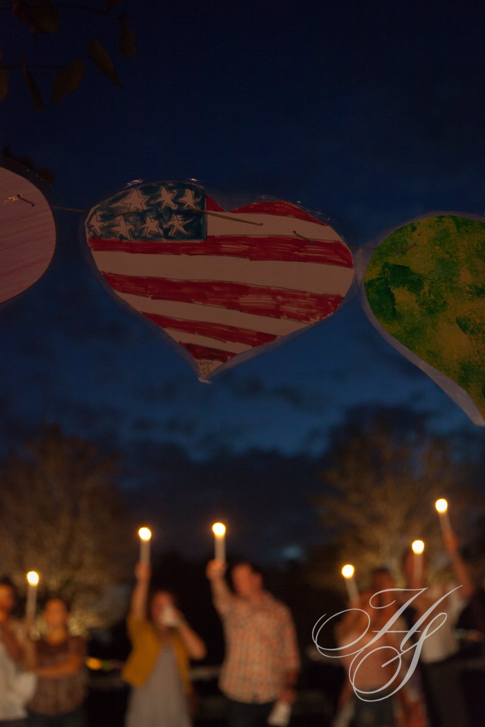 A group of people holding candles in the shape of hearts.
