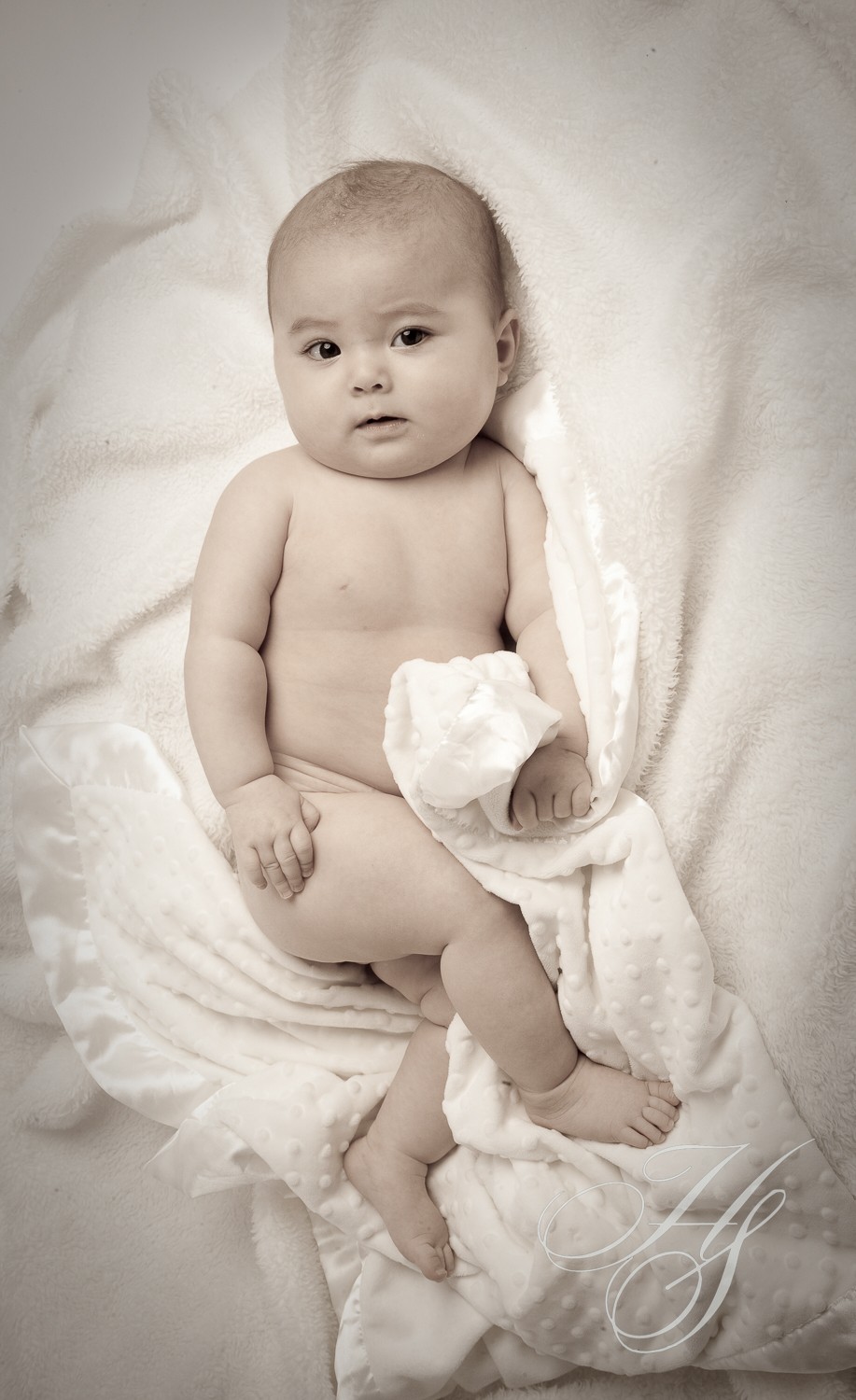 A baby is laying on the bed with his feet up.
