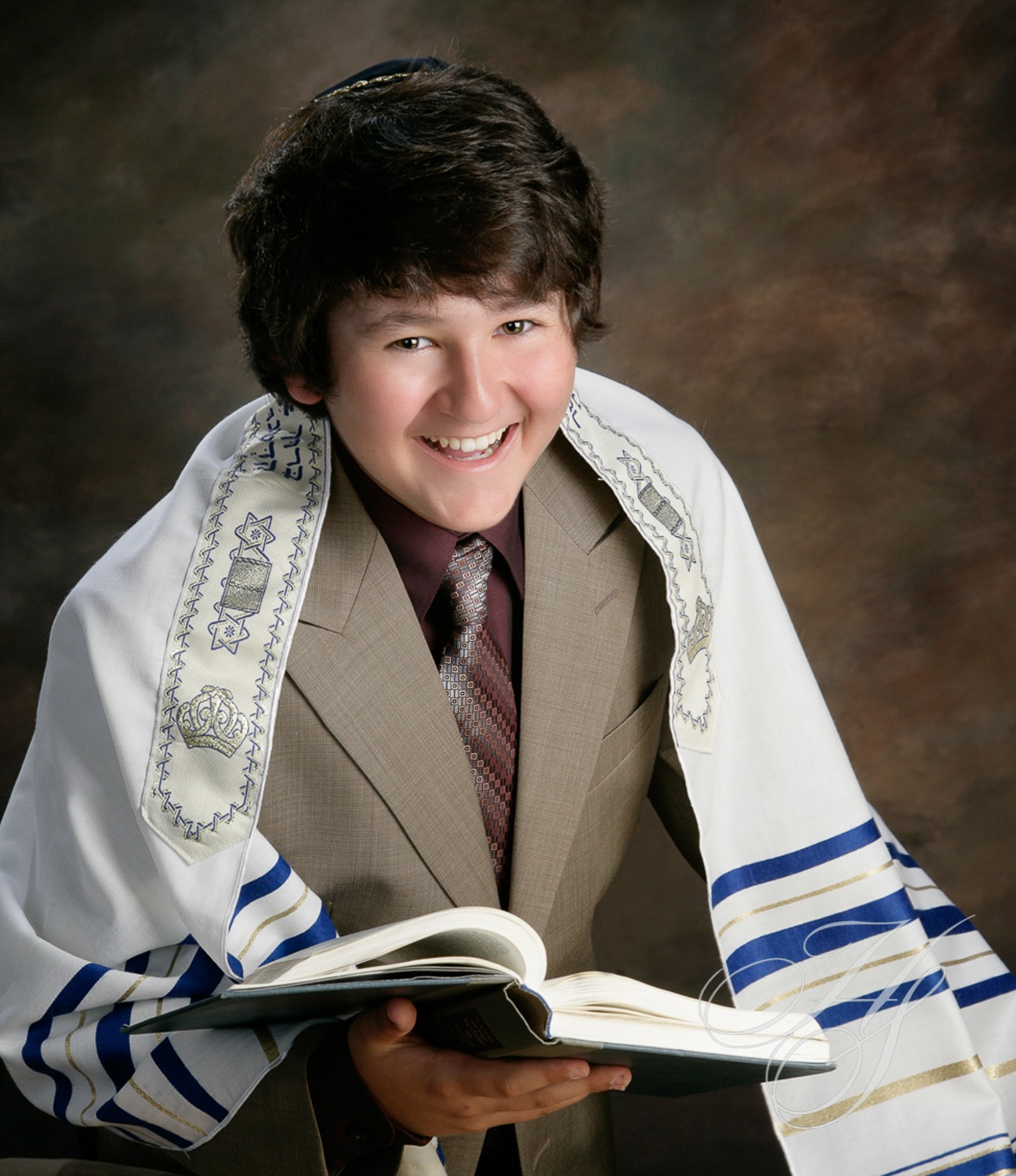 A young man in suit and tie holding open book.