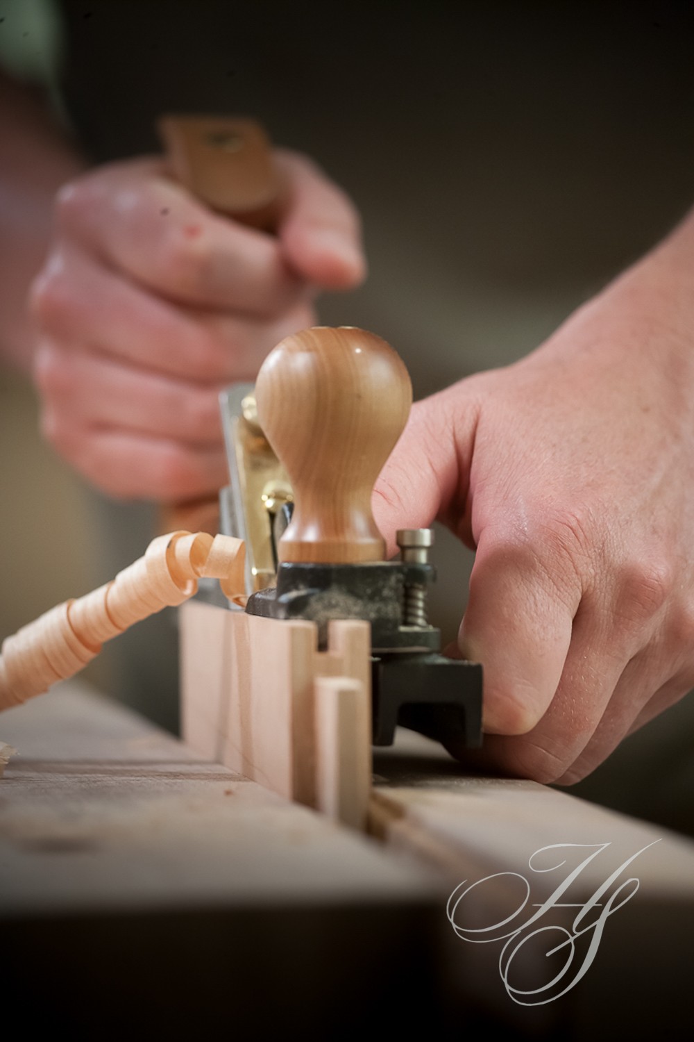 A person using a wood carving tool on wooden block.