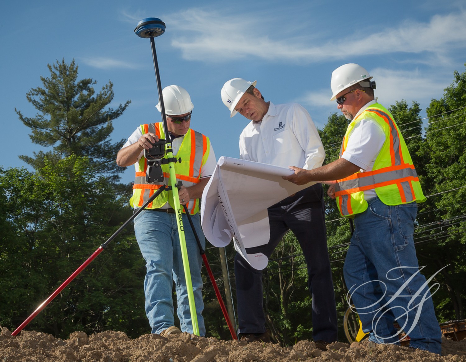 Three men in hard hats and safety vests are working on a construction site.