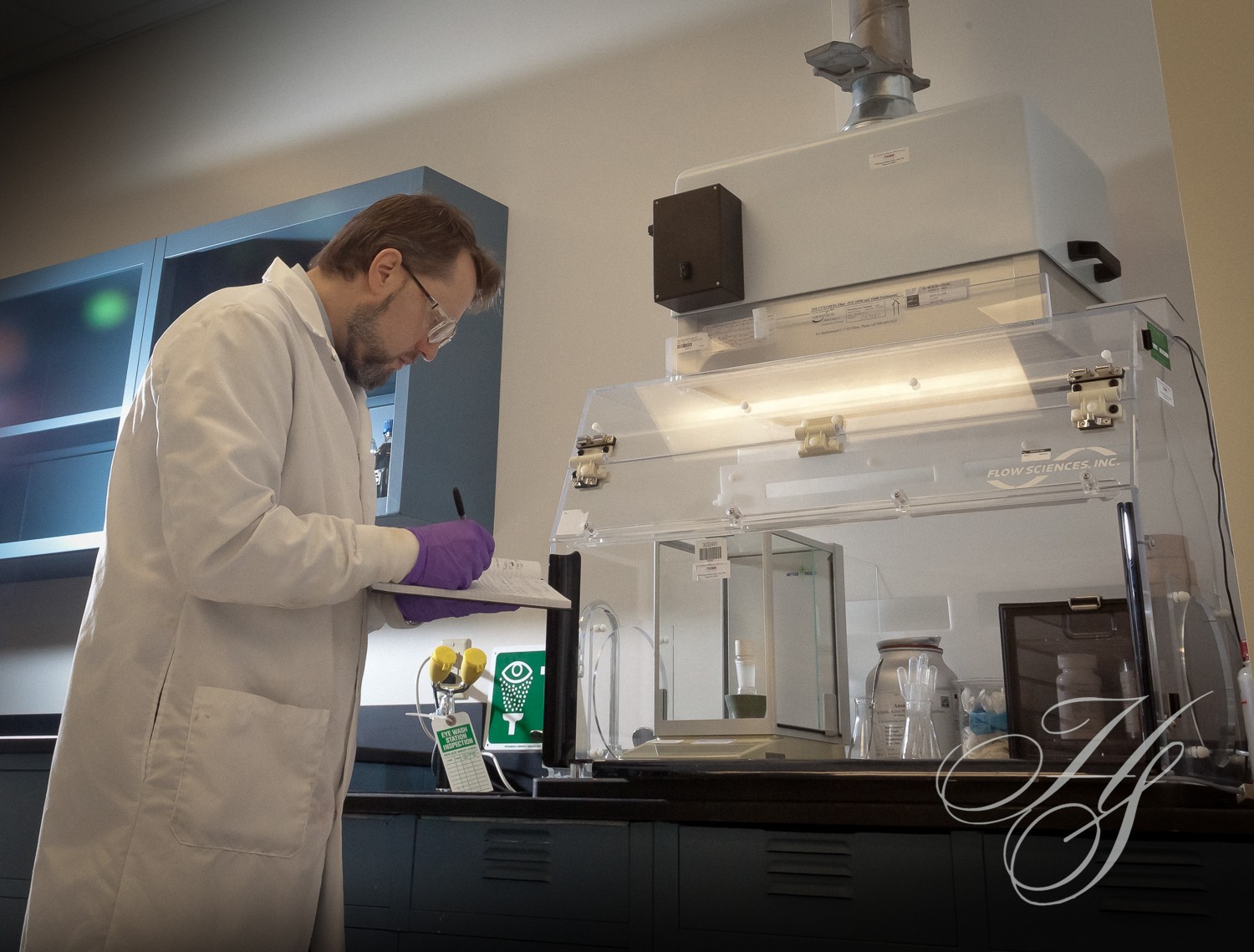 A man in white lab coat and purple glove working.