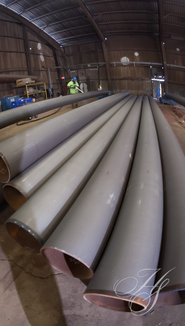 A bunch of pipes are laying in a warehouse