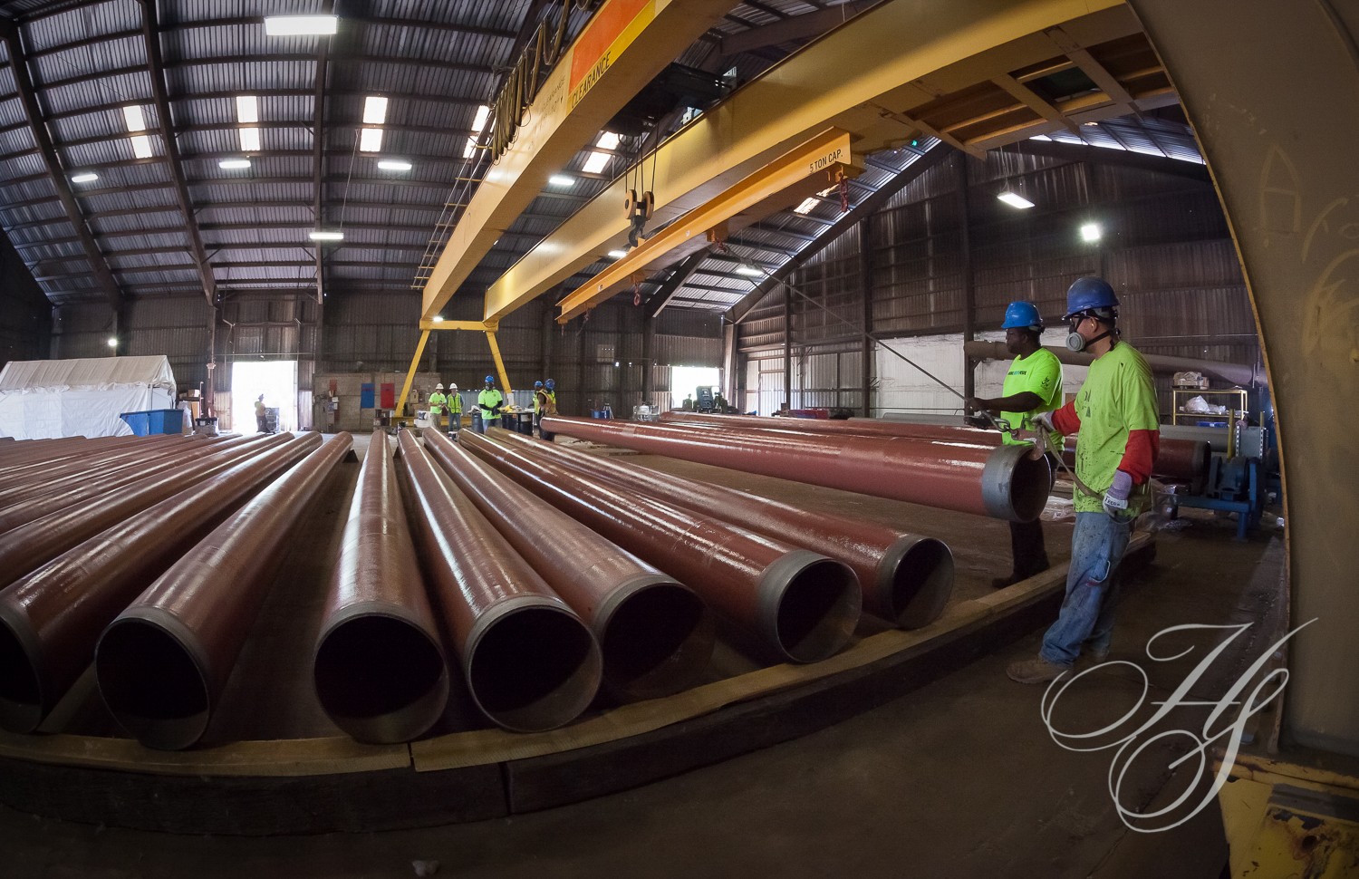 A group of men standing next to large pipes.