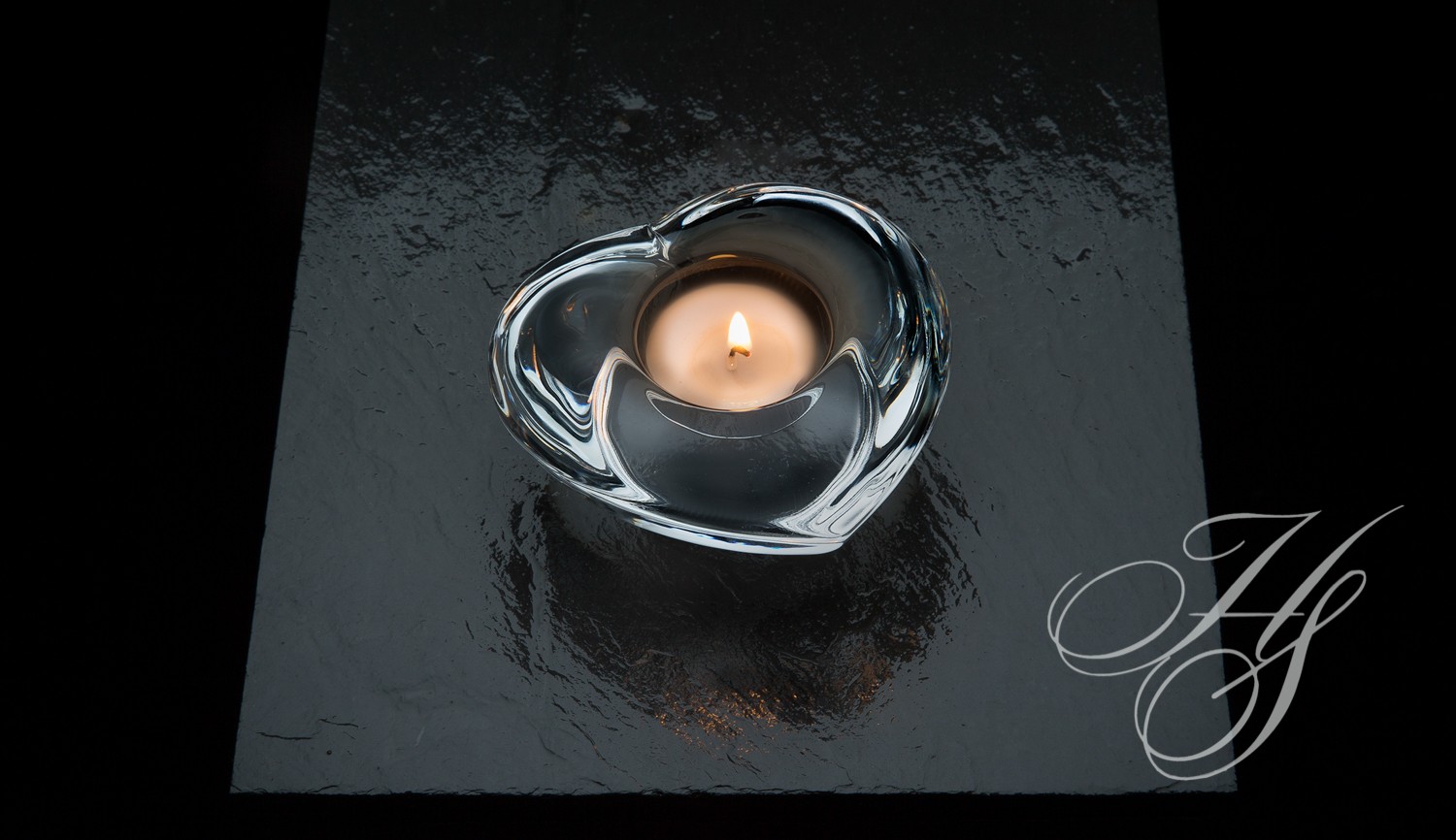 A candle in the shape of a heart on top of a table.