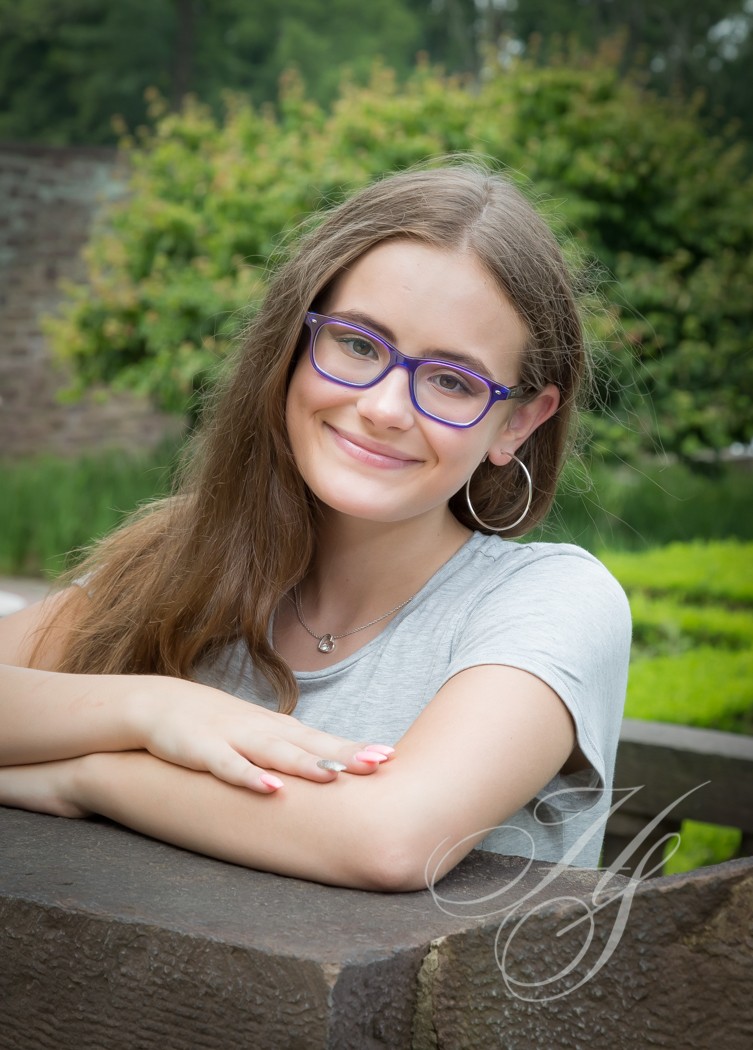A girl with glasses sitting on top of a bench.