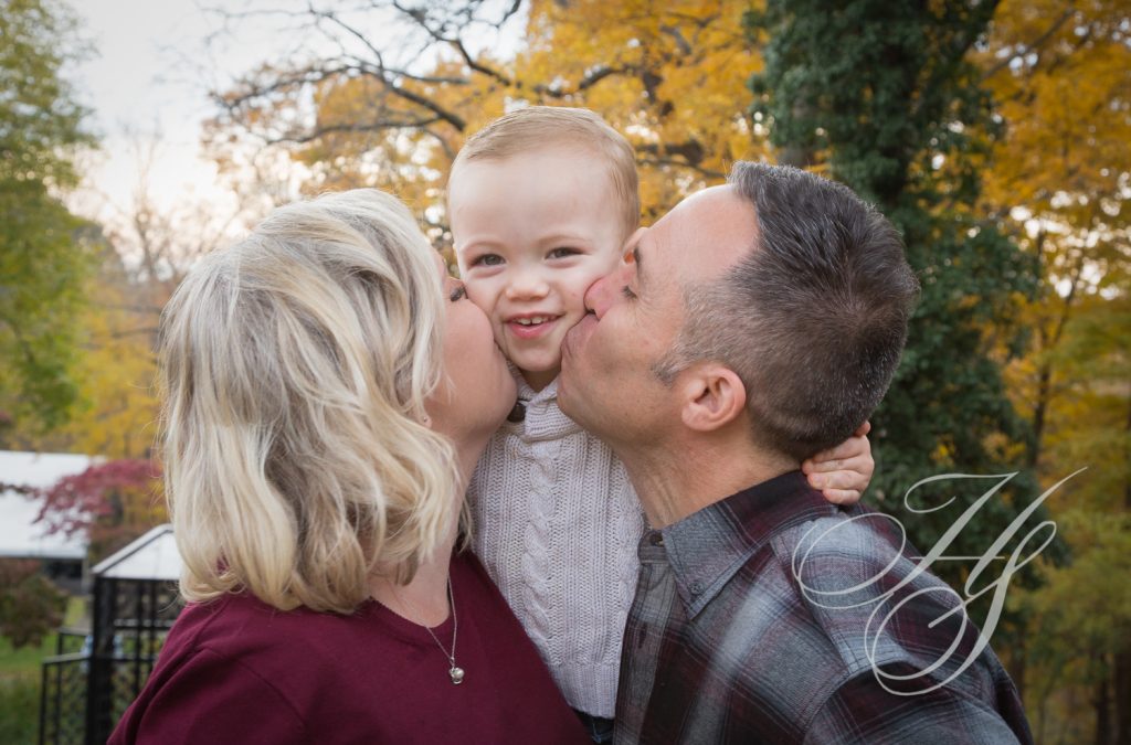 A man and woman kissing a baby boy.