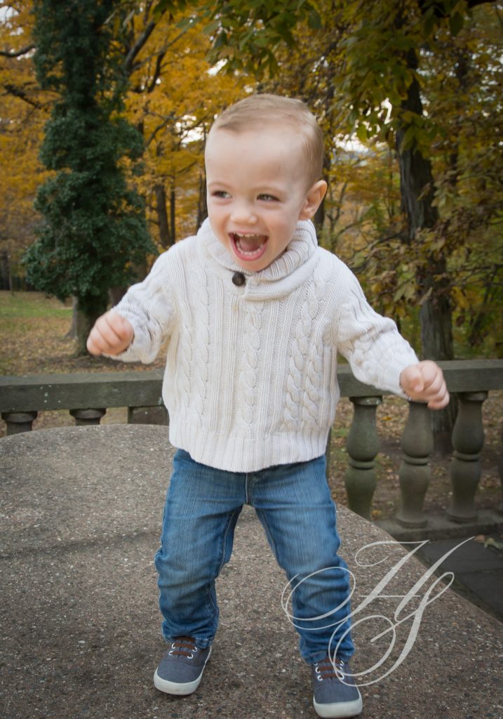 A young boy is standing outside in the fall.