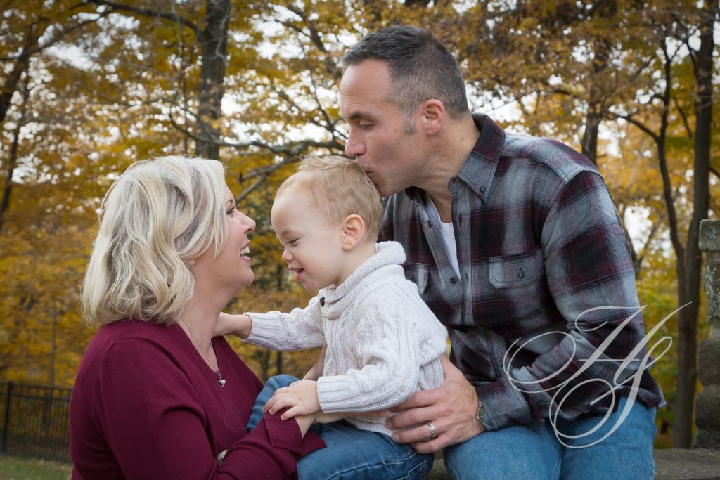 A man and woman kissing their son on the cheek.