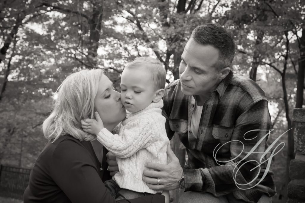 A man and woman kissing their baby boy.