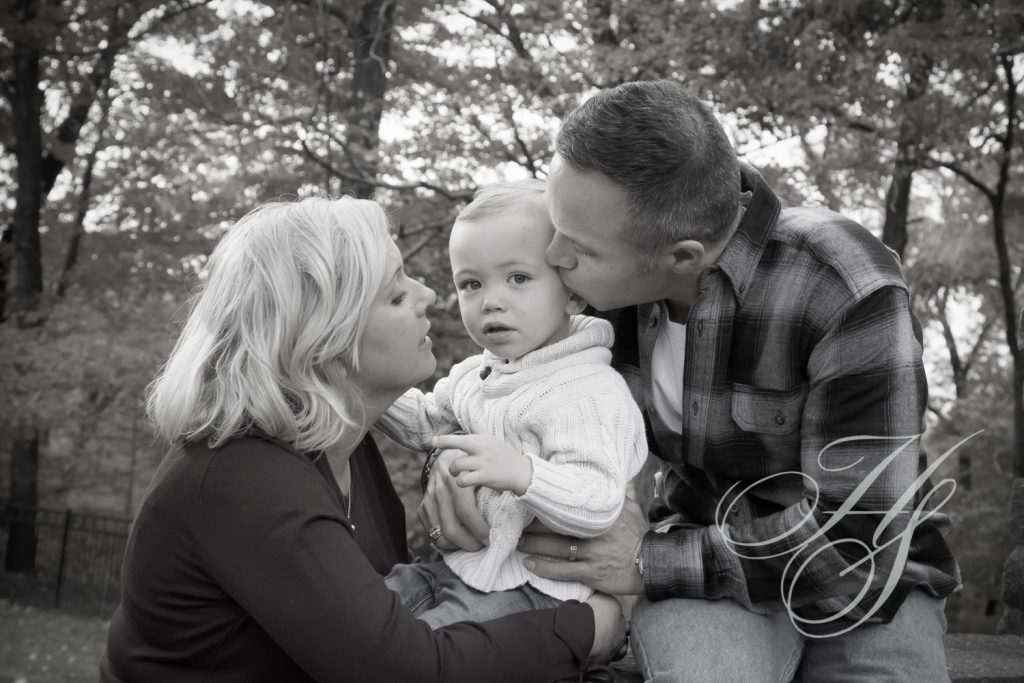 A man and woman kissing their baby boy.