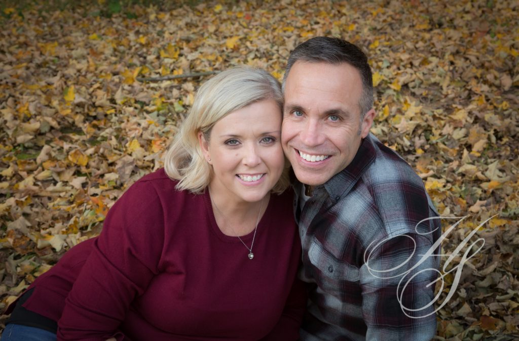 A man and woman sitting in the leaves.
