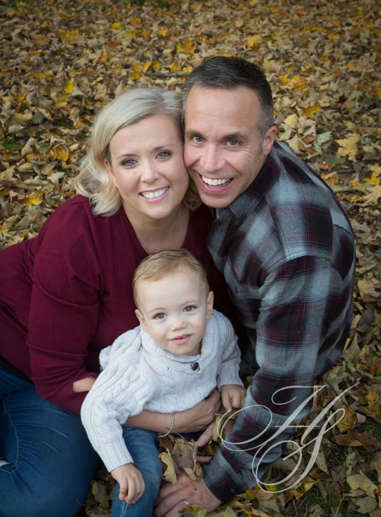 A man and woman holding a baby in the leaves.