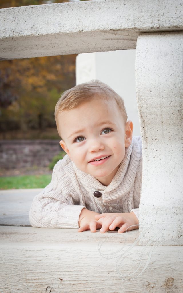 A young boy laying on the ground in front of a white pillar.