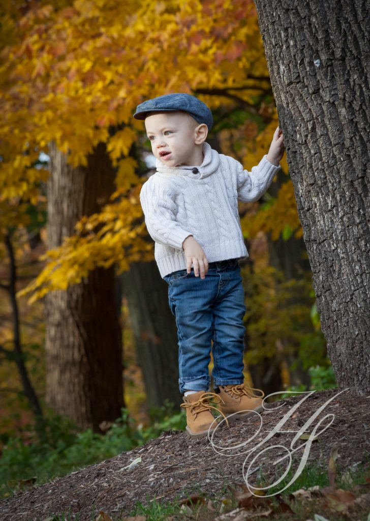 A young boy standing next to a tree.