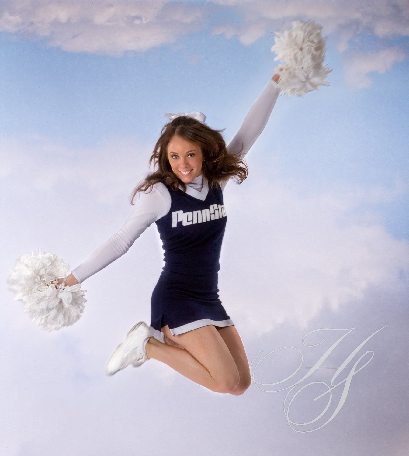 A cheerleader jumping in the air with her pom poms.