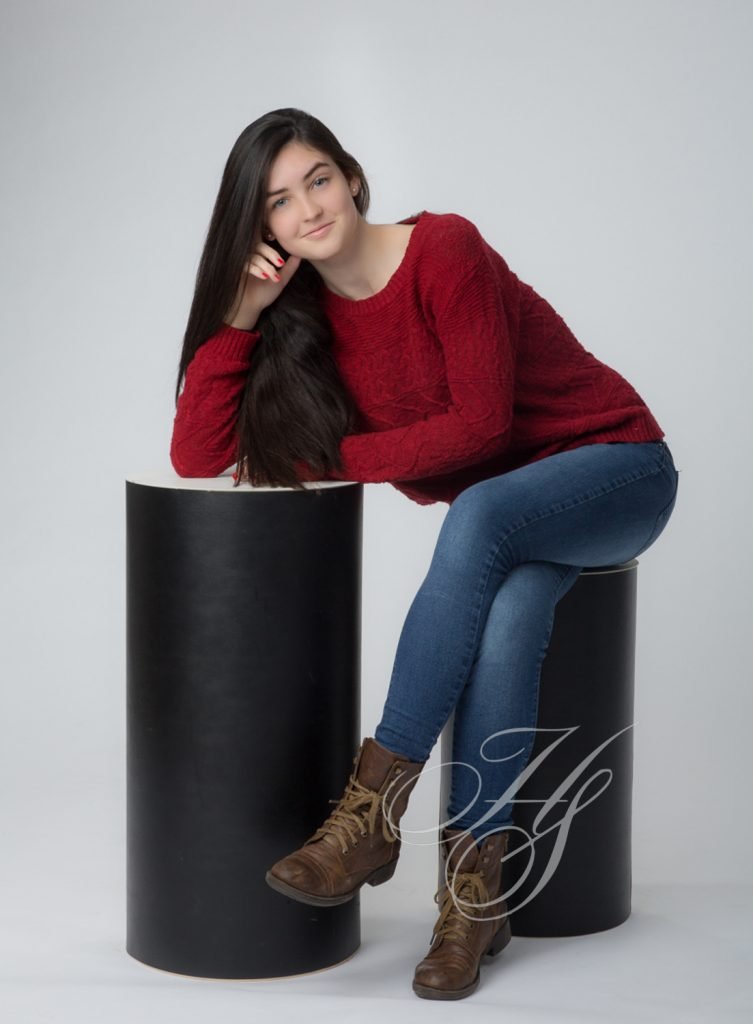 A girl sitting on top of a black cylinder.