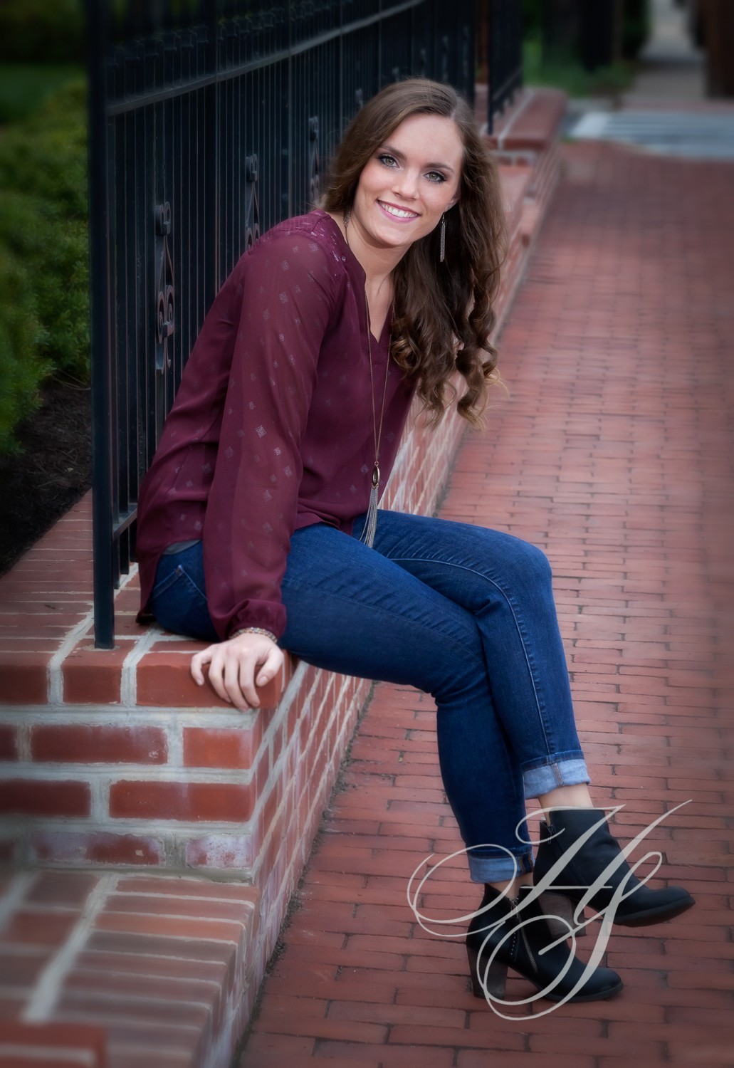 A woman sitting on the ledge of a brick wall.