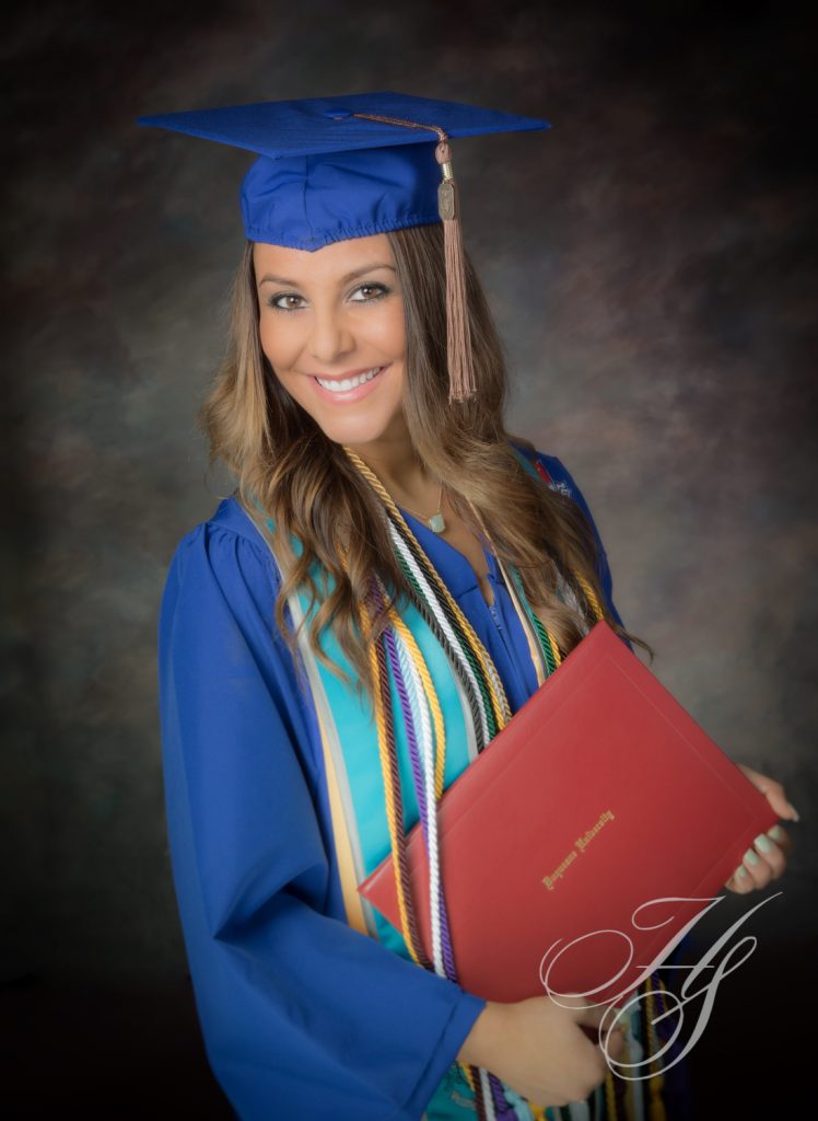 A woman in blue graduation gown holding red folder.