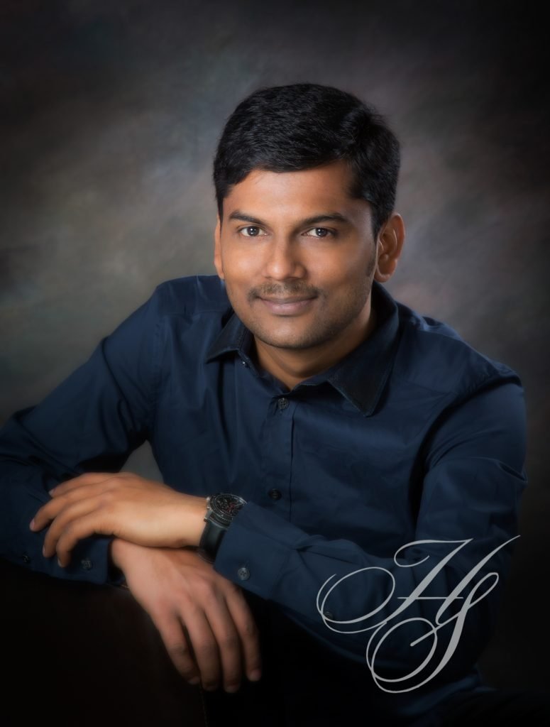 A man in a blue shirt is posing for the camera.