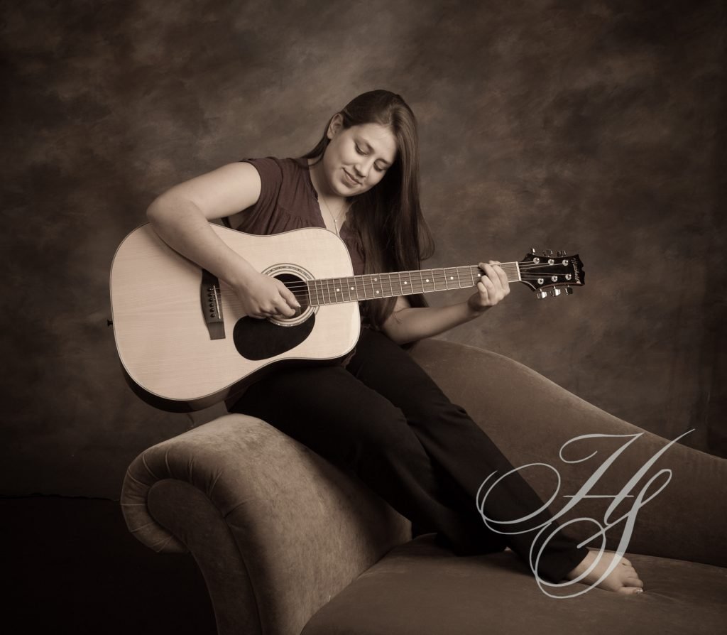 A woman sitting on top of a couch holding a guitar.