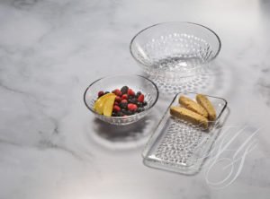 A bowl of fruit and two other bowls on the table.