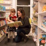 A woman and child are reading books in the library.