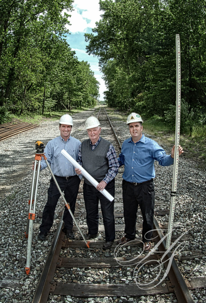 Three men in hard hats standing on a train track