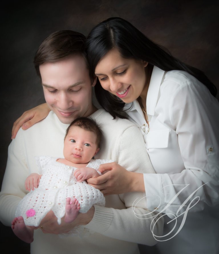 A man and woman holding a baby in front of a camera.